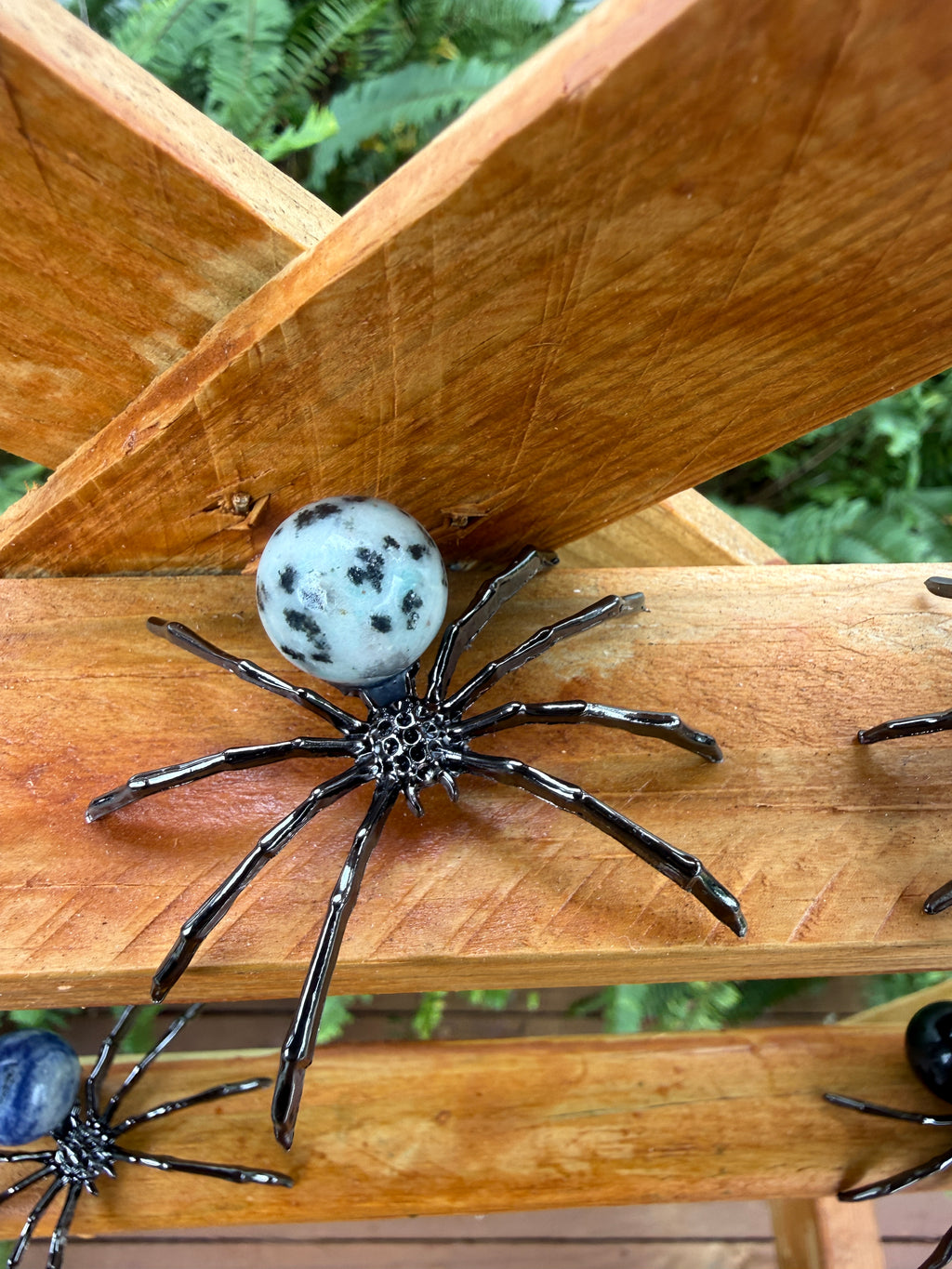 Decorative kiwi jasper spider with a ball on a wooden surface