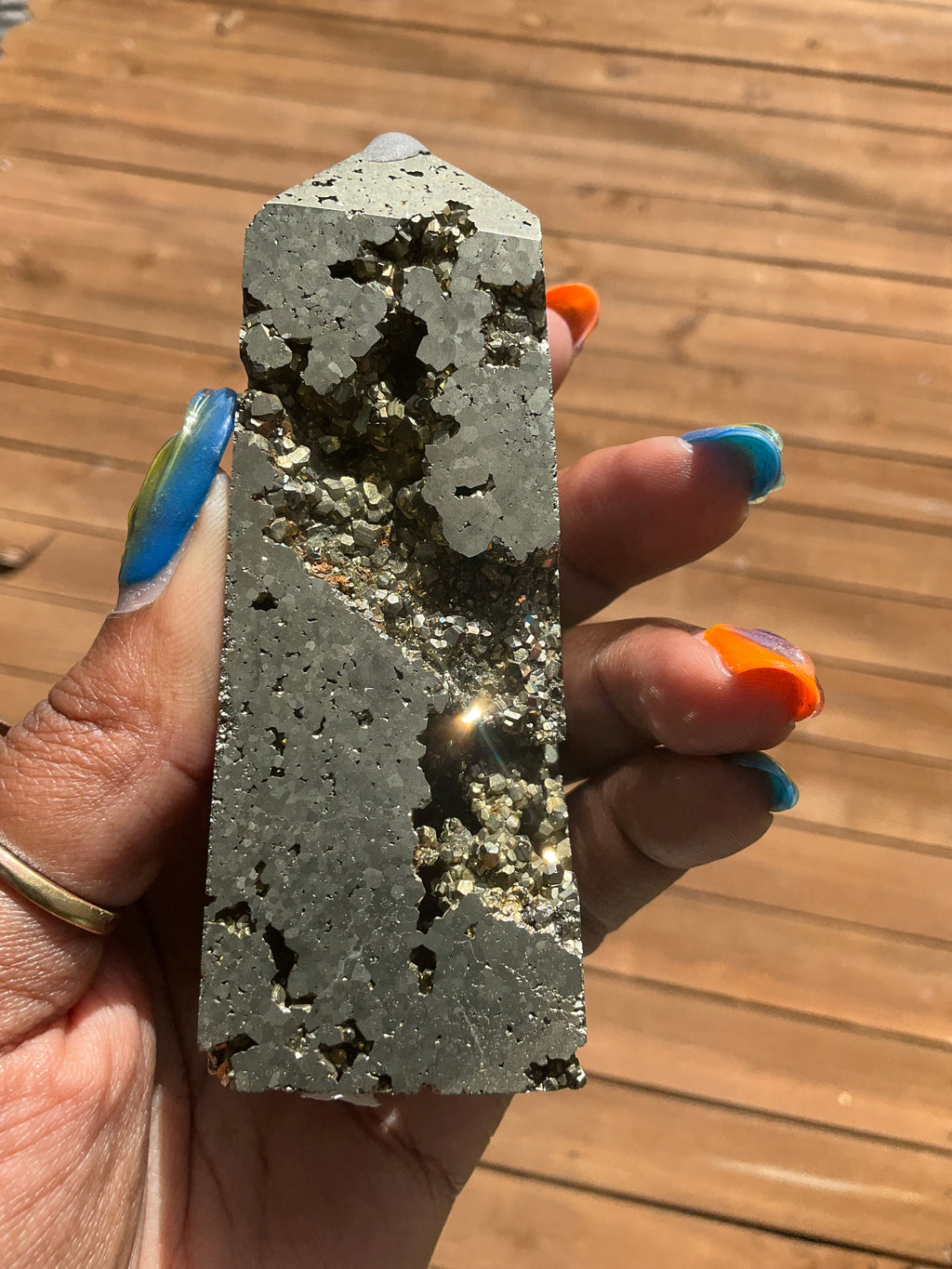 Hand holding a rough-textured silver stone or crystal against a wooden background